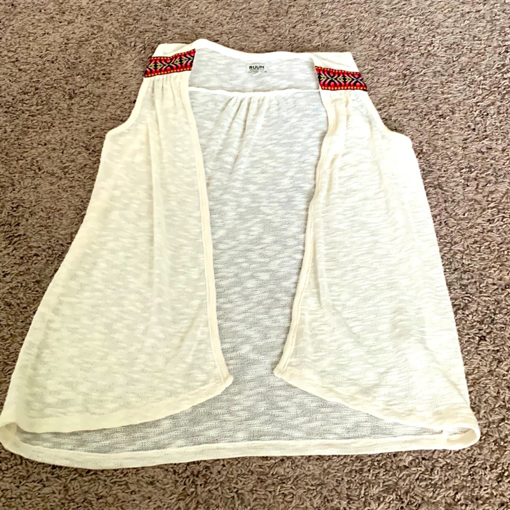 A white thin vest with a pattern on the front shoulders.